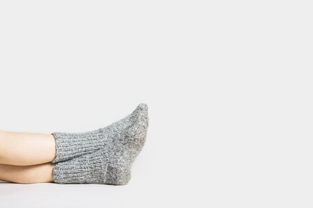 Woman sits on the floor in warm gray socks on a light background. Only legs visible.の写真素材