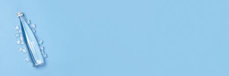 Glass bottle with clear water on a blue background with Ice cubes. Concept of health and beauty,...