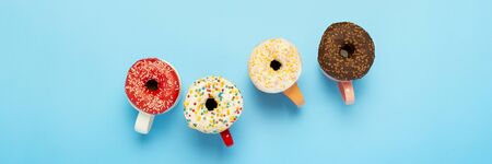 Tasty donuts and cups with hot drinks on a blue background. Concept of sweets, bakery, pastries,...