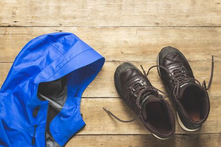 Hiking boots and jacket on a wooden background. The concept of hiking, tourism, camp, mountains, forest. Banner. Flat lay, top view.の写真素材