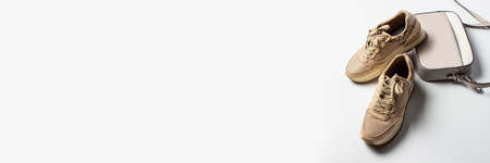 Sneakers and cross body bag on a light background. Accessories for a fashionable look. Flat lay, top view. Bannerの写真素材