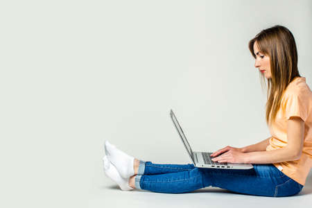 Young woman is reading a book while sitting on the floor on a light background. Education concept, exam preparation. Bannerの写真素材