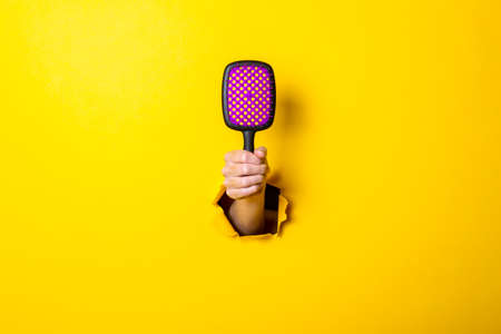Female hand holds a large hairbrush on a yellow background. Hair care.の写真素材