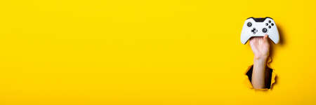 Man's hand holding a stick on a bright yellow background. Banner