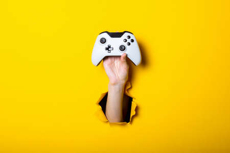 Female hand holds a joystick on a bright yellow background.の写真素材