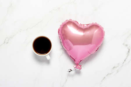 Cup with coffee and air balloon heart on a marble table. Concept of dinner, Valentine's Day, date,...