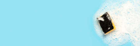 Soap foam from a cleaning agent and a cleaning sponge on a blue background. Cleaning concept,...