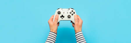 Hands holding a gamepad on a blue background. Banner. Concept games, video games.