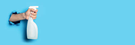 Man's hand holds a spray on a bright blue background. Banner