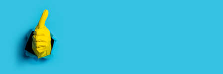 Hand in yellow glove shows thumb up class on a bright blue background. Banner