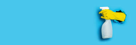 Hand in a yellow glove holds a spray on a bright blue background. Bannerの写真素材