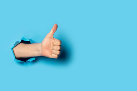 Male hand makes a hand up gesture on a blue background. Banner. Gesture all ok, like.の写真素材