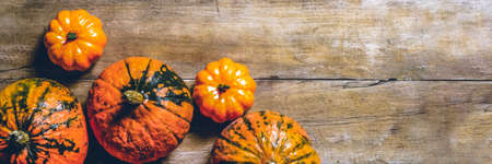 Pumpkins on a wooden background. Harvest concept, autumn, Halloween eve. Banner. Flat lay, top view.
