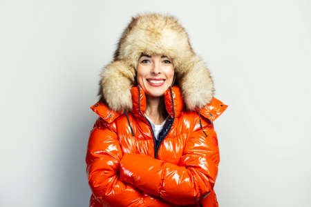 happy young girl in a red jacket holding her hands clasped on a light background. Concept gestures, fashion, trend.の写真素材