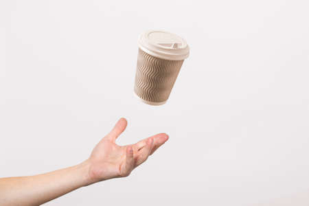 hand catches a cardboard glass on a light cardboard background. Concept of coffee, tea, advertising,...