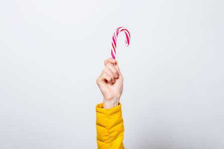 female hand holds loli pop on a light background. Banner. Concept Christmas, New Year, celebration.