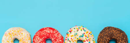Donuts of different types on a blue background. Concept of sweets, bakery ,. Banner. Flat lay, top...