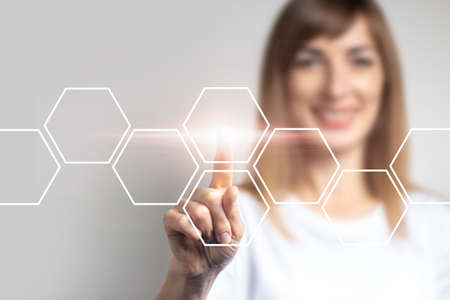 young girl points a finger at the virtual screen, icons are added on a light background. Banner. Concept business and digital technology.の写真素材