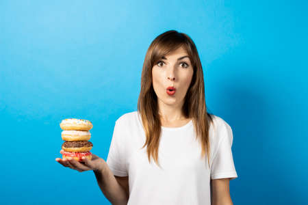 young girl holds four donuts on a palm on a blue background. Banner. The concept of diet, bright...