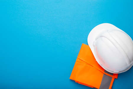 Construction hat and construction vest on a blue background. Concept for construction, renovation...