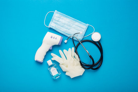 Digital non-contact thermometer, protective mask, latex gloves, medical stethoscope and sanitizer on...