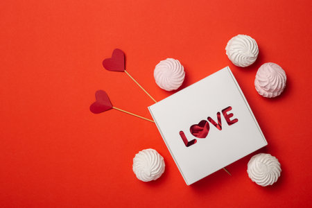 Gift box with the text Love, sweets and hearts on a stick on a red background. Composition Valentine's Day. Banner. Flat lay, top view.の写真素材