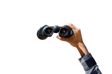 Male hand are holding binoculars on white isolated background. Banner. Flat lay, top view.の写真素材