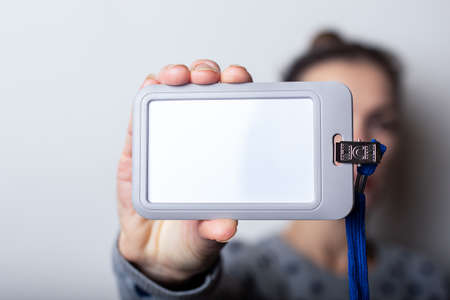 Young woman holding badge, name tag close up on light hill backgroundの写真素材