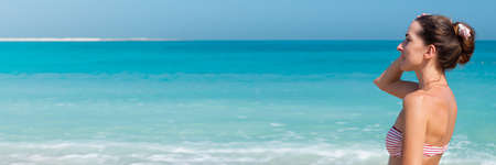 Young woman in a swimsuit against the background of the sea and blue sky. Bannerの写真素材