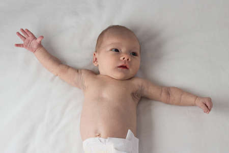 The Little Child in the Diaper, Baby, lies on a white bed. White background.の写真素材