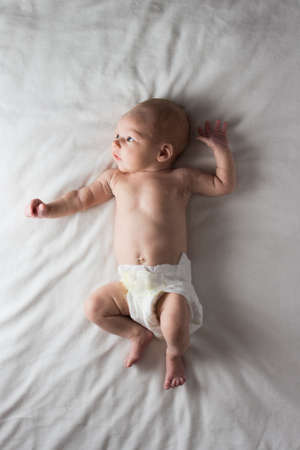 The Little Child in the Diaper, Baby, lies on a white bed. White background.の写真素材