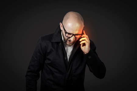 Male businessman with an evil face in a white shirt and dark cloak talks and shouts by telephone on...