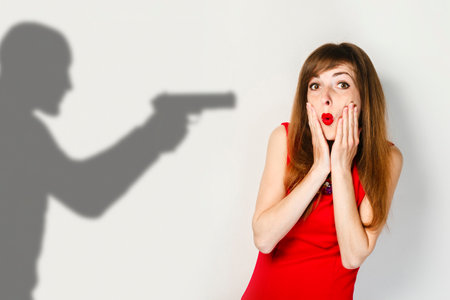 Young girl with a frightened face in a red dress on a light background. Concept scare, protection