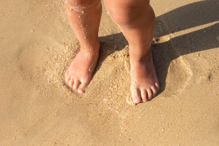 children's two feet stand on the sand, on the beach. Travel, vacation