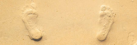 footprints from two feet on the sand of the beach. Top view. Banner