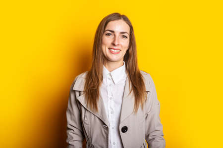 Young woman in a coat on a yellow background. Banner.の写真素材