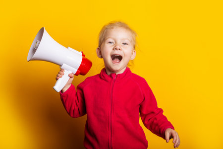 girl shouts holding a megaphone on a bright yellow background.の写真素材
