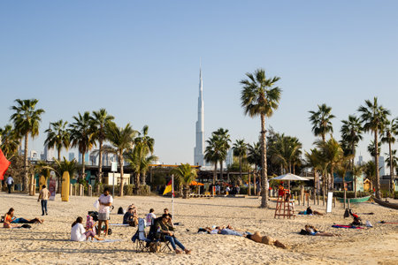 sandy beach with people resting, overlooking palm trees and skyscraperのeditorial素材