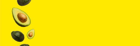 pitted avocado and whole avocado fly in the air on a yellow background. Top view, flat lay. Banner.