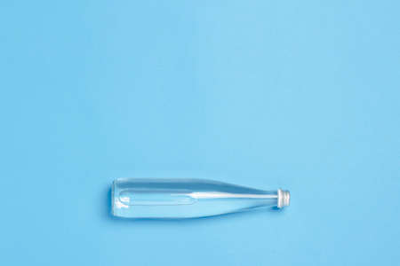Glass bottle with clear water on a blue background. Concept of health and beauty, water balance, thirst, heat, summer. Flat lay, top view.の写真素材