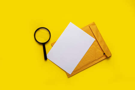 magnifying glass, blank white sheet and envelope on a yellow background.の写真素材