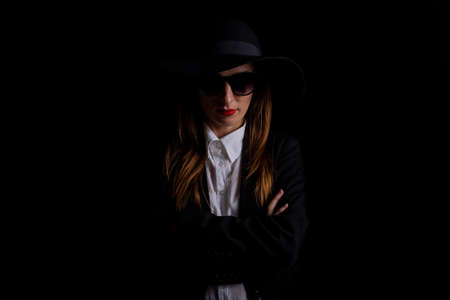 business woman in a black hat, glasses on a black background.