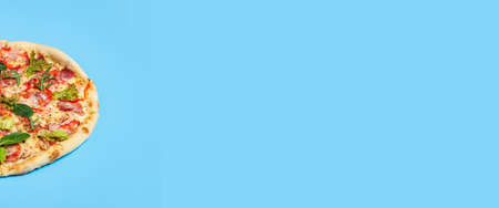 whole pizza fresh hot on a blue background. Top view, flat lay. Banner.