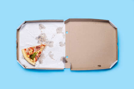 slice of hot fresh pizza lies in a cardboard package on a blue background. Top view, flat lay.