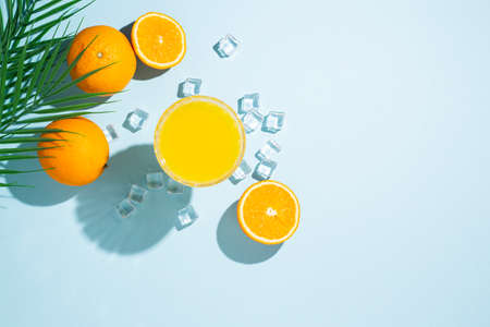 glass with orange juice, orange and ice cubes on a blue background. Top view, flat lay.の写真素材