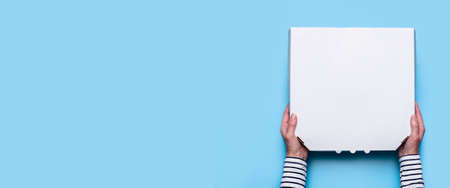 female hands open the package with a bird on a blue background. Top view, flat lay. Banner.