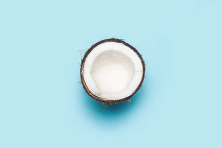 open half of a coconut on a blue background. Top view, flat lay.の写真素材