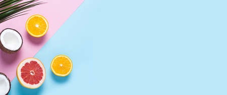 exotic fruits on a blue pink background. Coconut, orange, grapefruit. Top view, flat lay. Banner.の写真素材