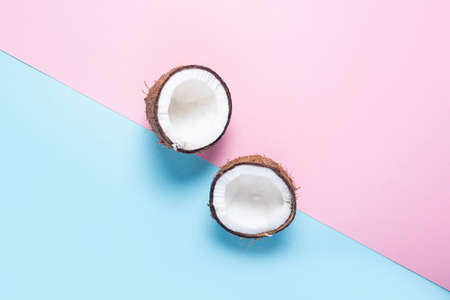 open coconut two halves on a pink-blue background. Top view, flat lay.の写真素材
