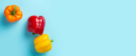 Three fresh bright sweet peppers on a blue background. Top view, flat lay. Banner.の写真素材